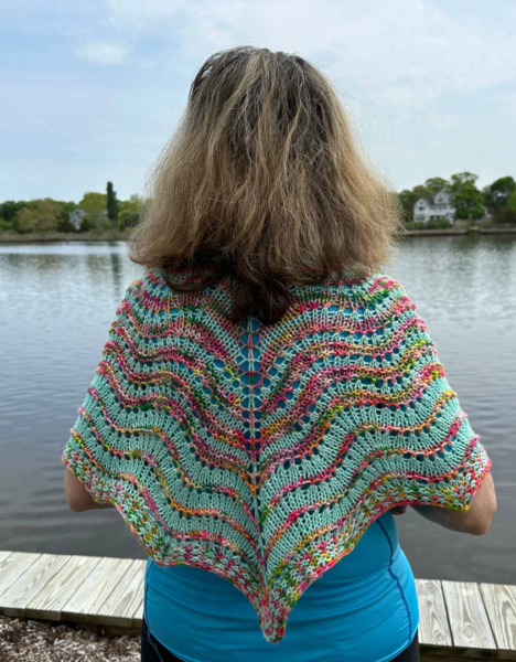 June 2023 KAL shawl shown modelled outside with the model facing an inlet on a partly cloudy day